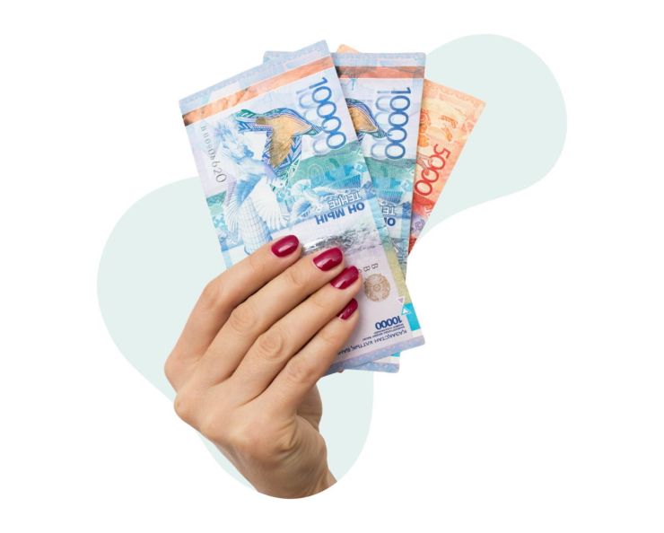 В женской руке кредит наличными: две банкноты по 10 тысяч тенге и одна банкнота в 5 тысяч тенге