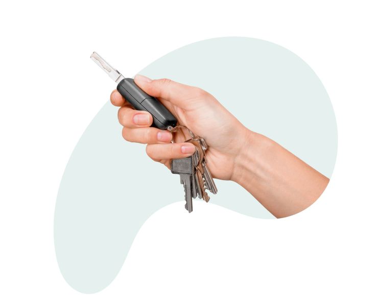 В женской руке связка ключей, из которых один от нового автомобиля, который приобретен благодаря автокредиту