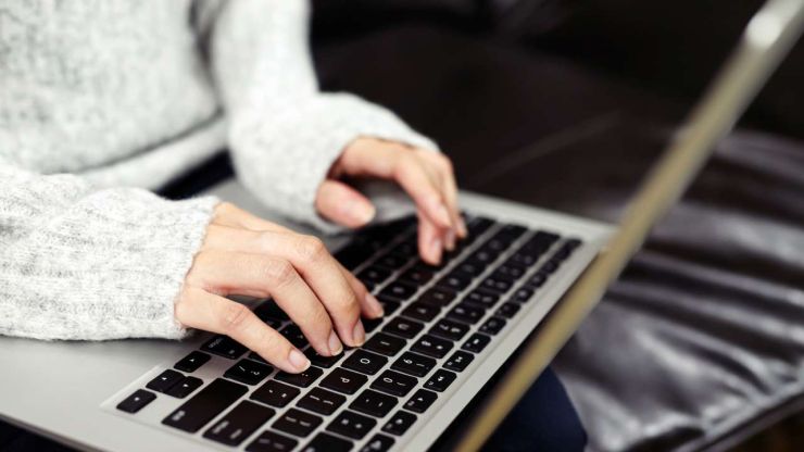 Девушка держит на коленях ноутбук, потому что хочет найти информацию, где в сети взять кредит без отказа
