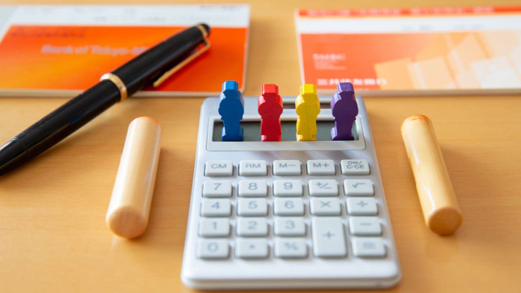 Калькулятор с фигурками людей на фоне банковской книжки и ручки – наследование кредитов среди родственников