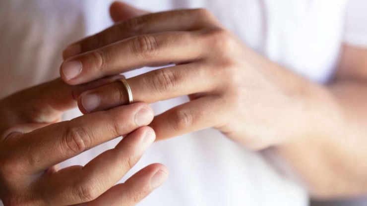 Мужчина со своего безымянного пальца снимает обручальное кольцо, потому что падал документы на развод