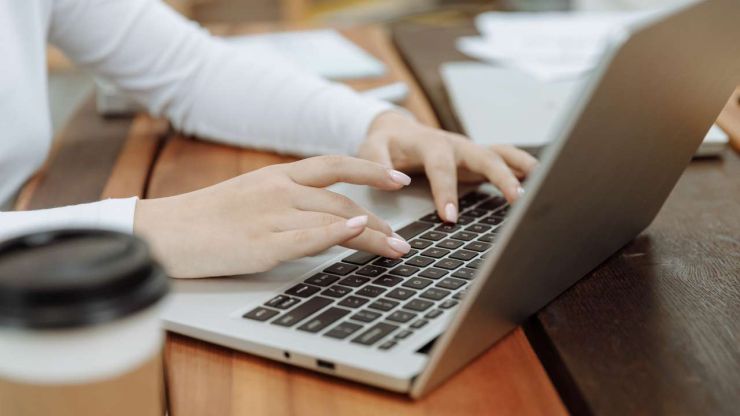 Женщина сидит за столом и в ноутбуке ищет информацию по юридическим последствиям при просрочке микрокредита