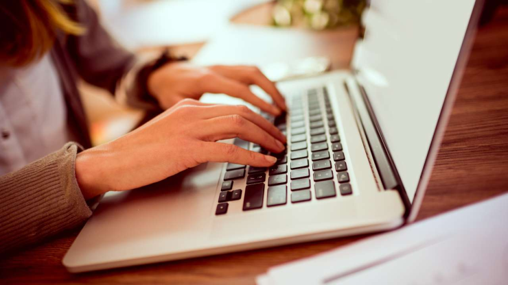 Крупным планом ноутбук, на котором женские руки через браузер ищут беззалоговые кредиты