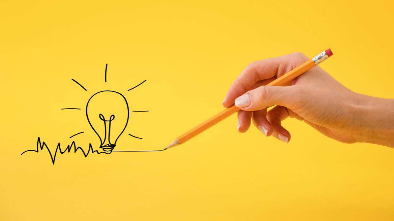 На желтом фоне женская рука простым карандашом рисует лампочку – идею умных финансовых решений
