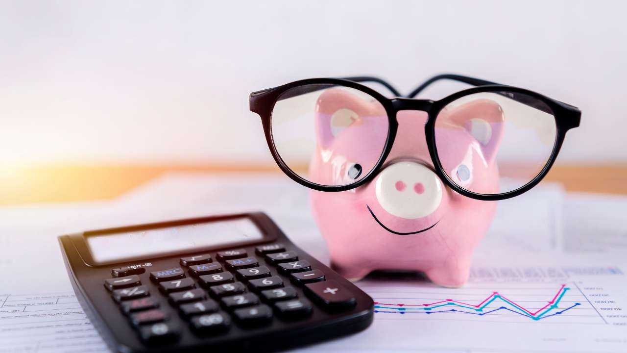 На столе стоит свинка-копилка в очках, калькулятор и документы запасного финансового плана