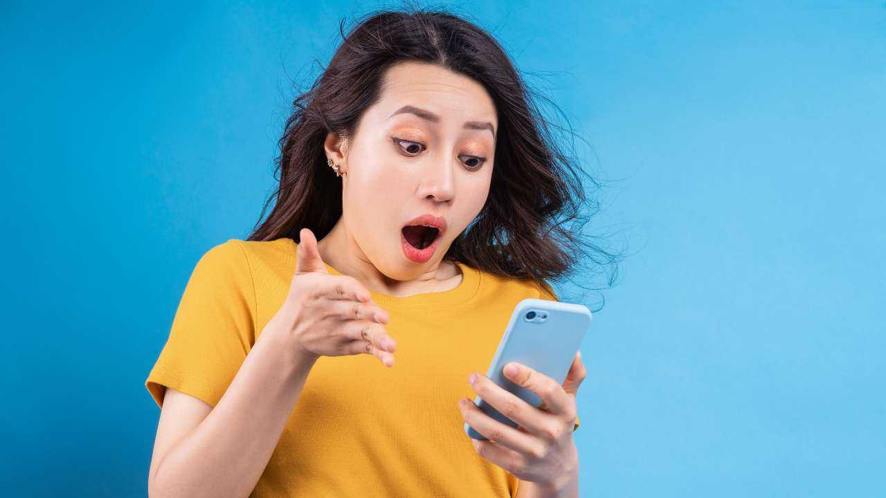 Девушка с приятным удивлением смотрит в экран телефона, на который ей прислали выгодные условия мини кредита онлайн