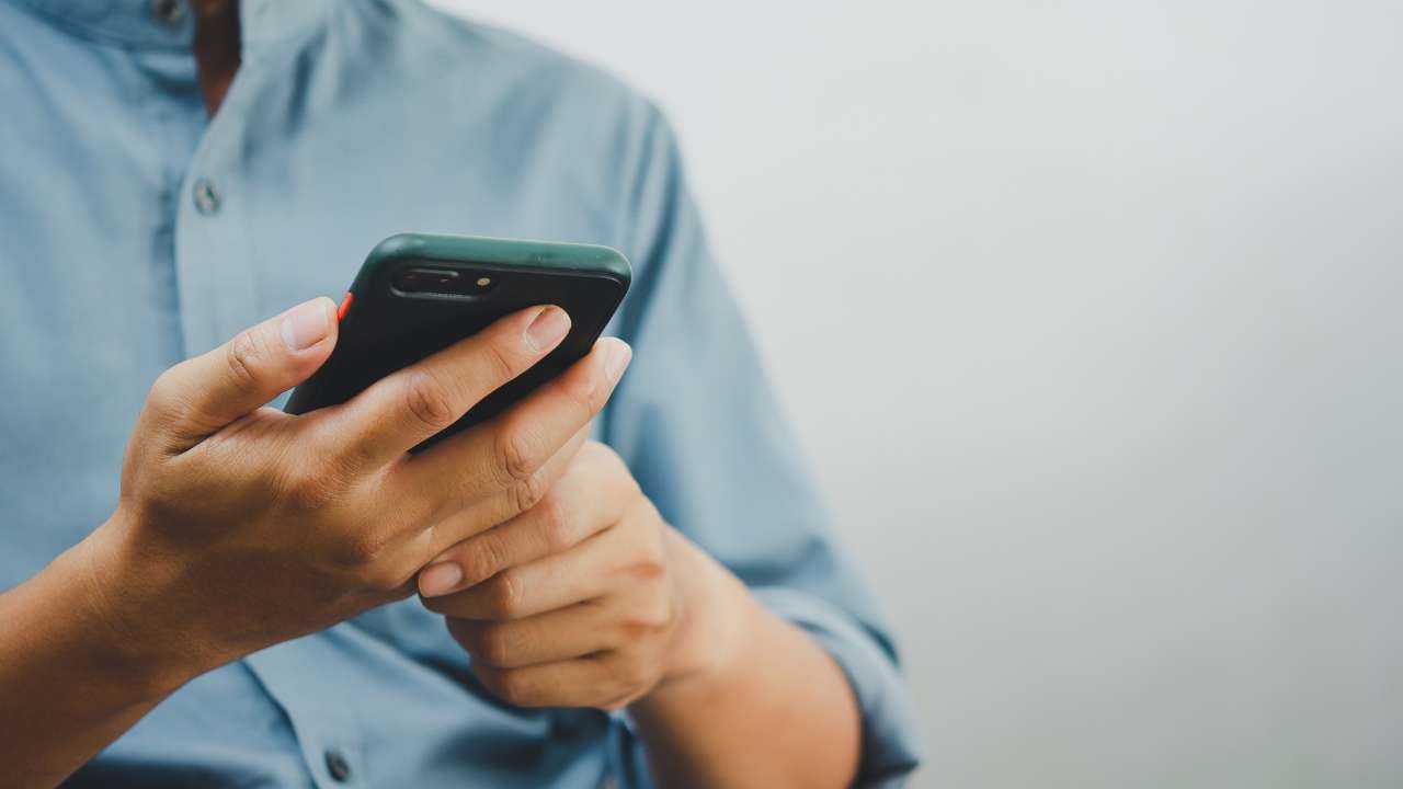 Человек в синей рубашке использует смартфон для оформления кредита в интернете
